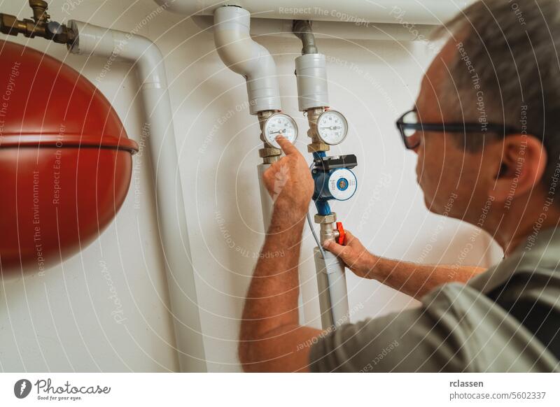 Heizungsmonteur überprüft Gasthermostat in einem Heizungsraum mit einer alten Gasheizung. Gasheizung Ersatz Verpflichtung Konzept Bild Brille Mann lesen