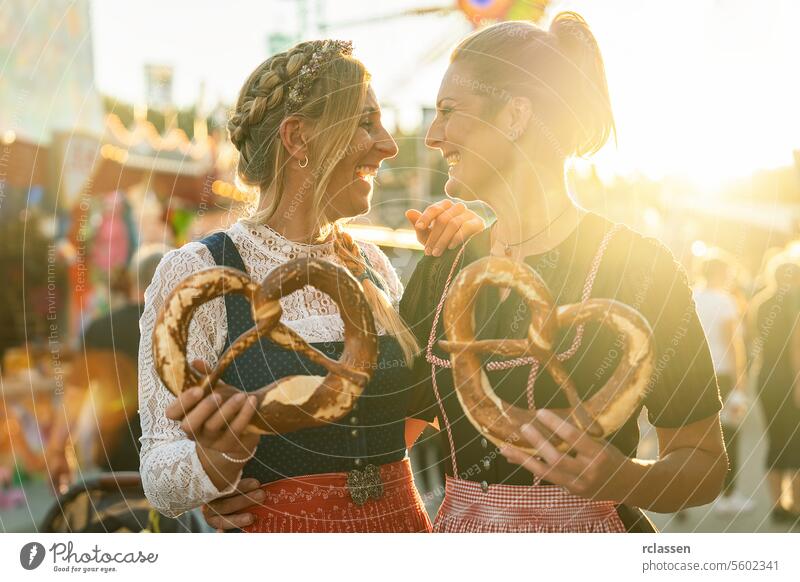 Zwei Freundinnen zusammen mit Brezel oder Brezen auf einem bayerischen Volksfest oder Oktoberfest oder in Tracht oder Dirndl in Deutschland Frau Party brezen