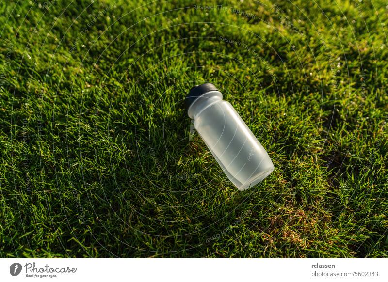 Wasserflasche liegt auf dem Rasen im Sonnenlicht. Sportgeräte Konzept Bild Gras Hydratation Fitness grün Gesundheit Wellness im Freien Übung Training