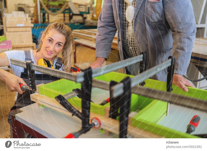 Auszubildender mit Gehörschutz klemmt Holz zum Verleimen in der Werkstatt professionell Kunsthandwerker Hobelbank Möbelindustrie Arbeiter Schnittholz