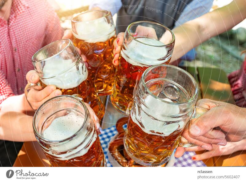 Fünf Freunde mit einem frischen Bier in einem Biergarten, Nahaufnahme auf Bierkrug oktoberst deutschland brezen Deutsch Bayern bayerisch Bar Feier jubelt Mann