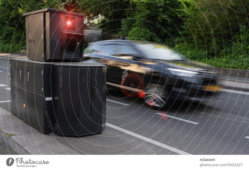 Geschwindigkeitskontrolle Kamera am Straßenrand mit einem Auto in hoher Geschwindigkeit Bewegungsunschärfe, Laub Hintergrund Radarkamera