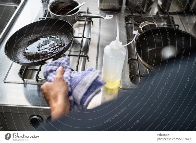 Chefkoch schwingt Öl eine beheizte Pfanne im Restaurant. Luxus-Hotel Kochen Konzept Bild. pendeln Hand Küche Küchenchef Ölgießen Profiküche Essen zubereiten
