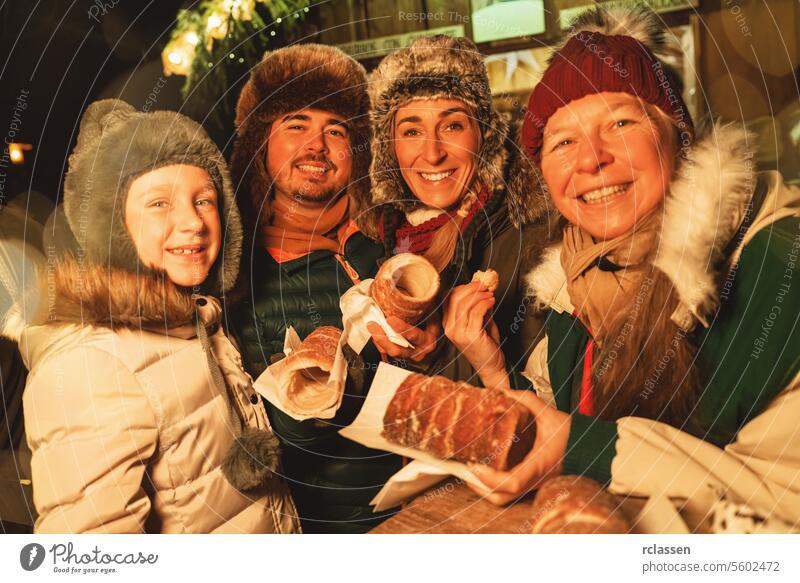 Glückliche Familie isst Baumstriezel oder Trdelnik vor einem Weihnachtsmarkt in Deutschland süß Snack Zucker Spirale baumstriezel trdelnik kurtoscalacs