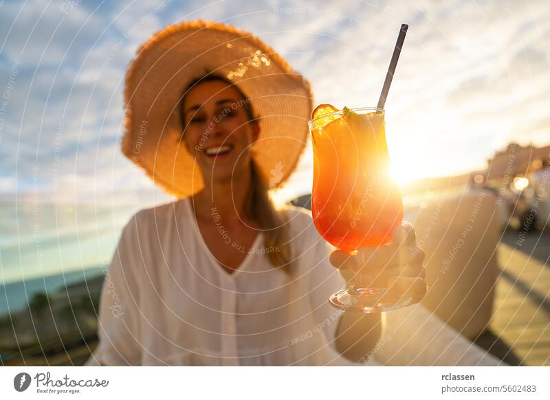 Lächelnde Frau mit Strohhut, die einen Cocktail vor dem Hintergrund eines Sonnenuntergangs hält Paradiesstrand Playa Küstenlinie tropisch Kanarienvogel Insel