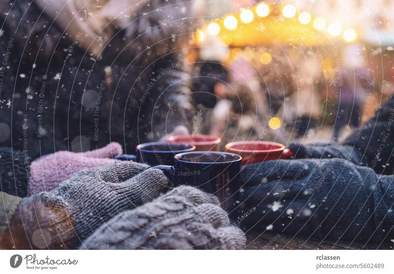 Hände in Handschuhen wärmen sich an dampfenden Glühweinbechern auf einem Weihnachtsmarkt, mit Platz für Ihren individuellen Text. Bowle Textfreiraum Deutsch