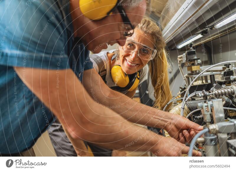 Zwei Arbeiter mit Schutzausrüstung bedienen Maschinen in einer Werkstatt Schreinerei Arbeitnehmer Teamwork Sicherheitseinrichtungen industriell Herstellung