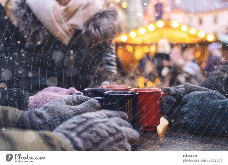 Hände in Handschuhen um dampfende Becher mit Glühwein auf einem Weihnachtsmarkt, mit Platz für Ihren individuellen Text. Bowle Textfreiraum Deutsch
