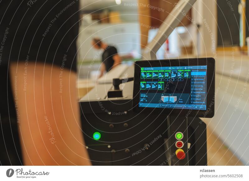 Touchscreen-Bedienfeld einer Maschine mit Arbeitern im Hintergrund in einer Werkstatt Arbeitnehmer Schreinerei Holzbearbeitung industriell Technik & Technologie
