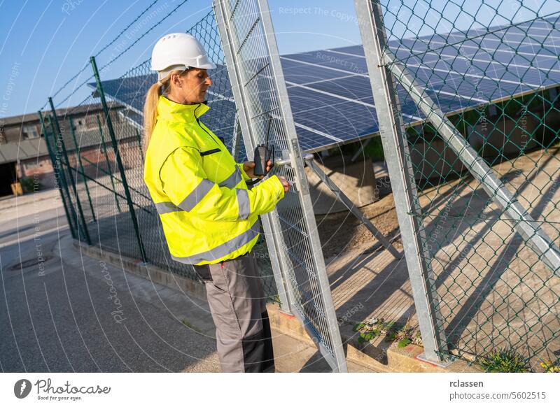 Techniker in Warnweste an einem Tor mit Walkie-Talkie in einem Solarpark. Alternative Energie ökologisches Konzept Bild. erneuerbare Ressource
