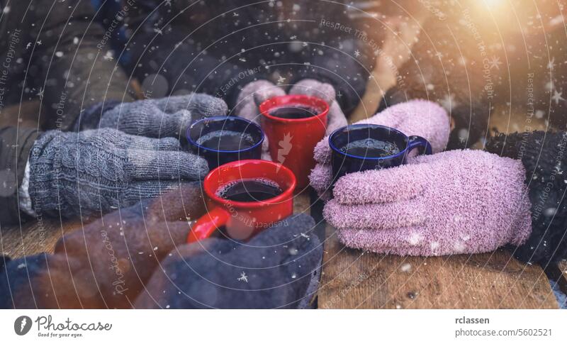Becher mit Glühwein auf einem Tisch, umgeben von behandschuhten Händen im Schnee Bowle Weihnachtsmarkt Deutsch Frohe Weihnachten Tasse Kakao Tassen