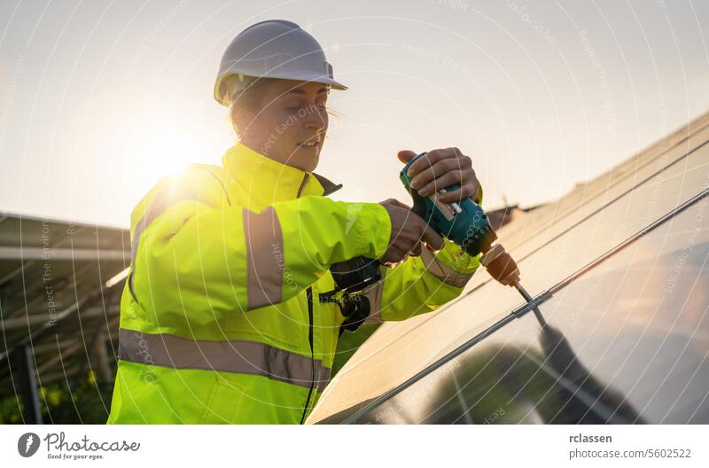Techniker bei der Montage von Sonnenkollektoren mit einem Akkubohrer bei Sonnenuntergang. Alternative Energie ökologisches Konzept Bild. Meisteringenieur