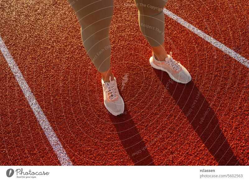 Nahaufnahme der Beine einer Sportlerin an der Startlinie einer Laufbahn Sportbekleidung Laufschuhe Fitness Vorbereitung Athletenbeine Leichtathletik Konkurrenz