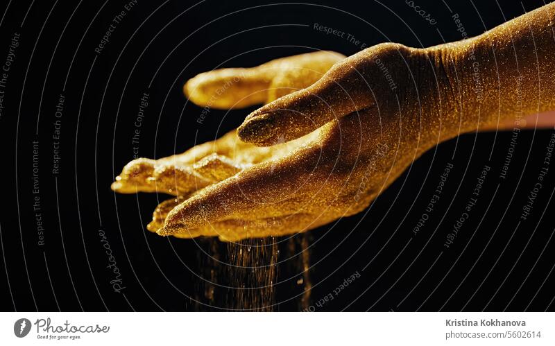 Golden glitzernde Frau Hände mit Staub, Sand auf schwarzem Hintergrund. Leben Momente. Dekoration & Verzierung dekorativ Emaille schön Glamour Glitter gold Haut