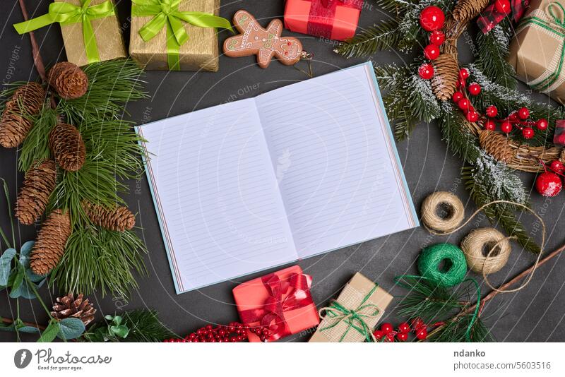 Geöffnetes Notizbuch mit leeren Blättern auf dem Tisch inmitten der Weihnachtsdekoration, Ansicht von oben Feiertag Überraschung Geschenk Notebook schreibend