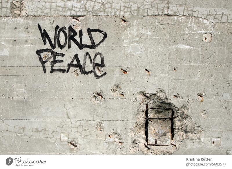 world peace schriftzug an einer wand mit munitionseinschlägen weltfrieden friedlich pazifismus pazifistisch graffiti streetart mauer fassade ziel forderung