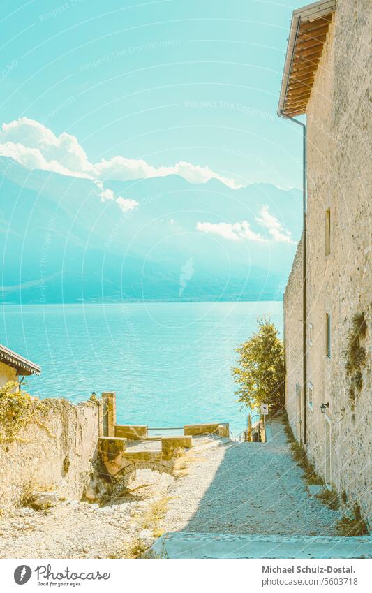 Malerischer Blick vorbei an Bruchsteingebäuden auf den Gardasee und den Monte Baldo Lago garda italien lombardei wasser hafen seascape port pittoresk seeblick