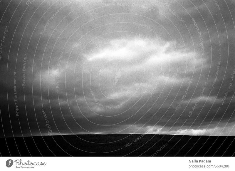 Landschaft und Wolken analog Analogfoto sw schwarzweiß Schwarzweißfoto Feld Himmel grau Bewölkung düster Lichtblick Dunkelheit