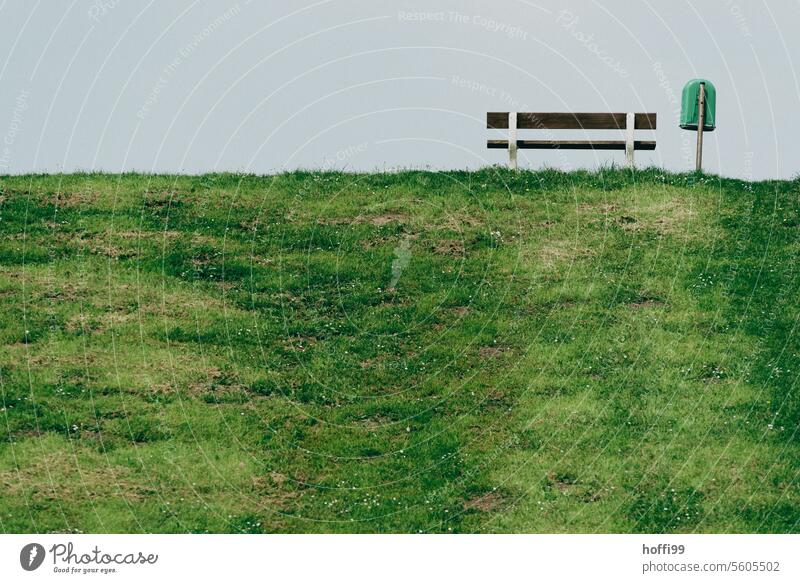 Bank und Mülleimer auf einem grünen Deich minimalistisch Minimalismus Einsamkeit Windstille Himmel Menschenleer Natur Erholung Parkbank sitzen Sitzgelegenheit