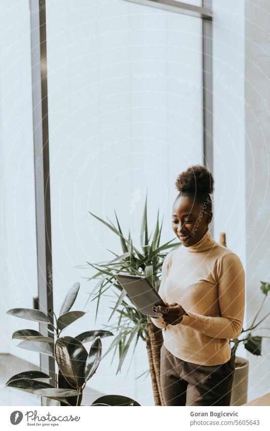 Eine junge afroamerikanische Geschäftsfrau mit digitalem Tablet an der Wand im Büro Erwachsener Afrikanisch Amerikaner schwarz Business Geschäftsleute