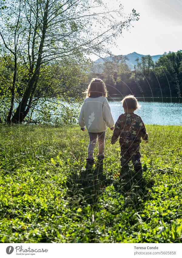 Kinder, die gemeinsam auf dem Feld spazieren gehen Kindheit Natur Spaß Glück Fröhlichkeit sonnig See Freude im Freien Urlaub aktiv Landschaft grün Gegenlicht