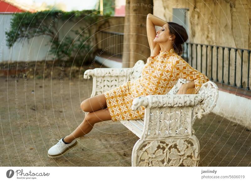 Sinnliche Frau sitzt mit geschlossenen Augen auf einer Bank im Tageslicht Model ruhen sich[Akk] entspannen Verlockung trendy Stil sinnlich jung Kleid Dame