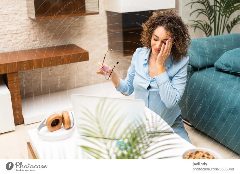 Erschöpfte Frau mit Laptop im heimischen Wohnzimmer freiberuflich müde Kopfschmerzen Arbeit erschöpft Stress Überarbeitung benutzend heimwärts abgelegen