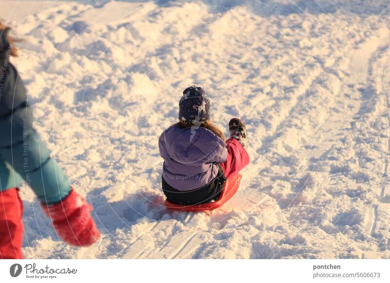 zwei kinder beim schlittenfahren, rodeln. bob zipfelbob schnee winter kinderspiel spaß winterkleidung bunt handschuhe zuschauen kalt weiß Außenaufnahme