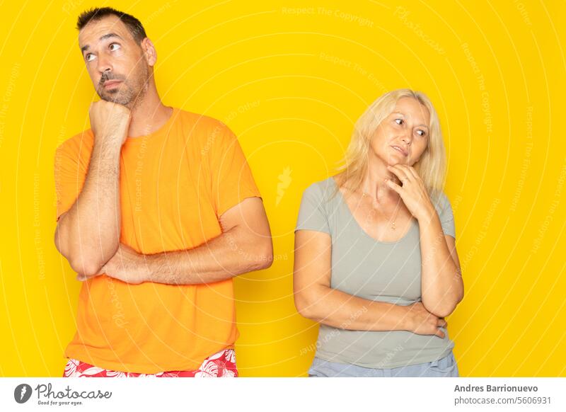 Contemplation of two lovers caucasian 40s couple spouses Ehefrau und Ehemann Freund und Freundin Blick nach oben, Planung für die Zukunft, nachdenklich und nachdenklich Menschen isoliert in gelb