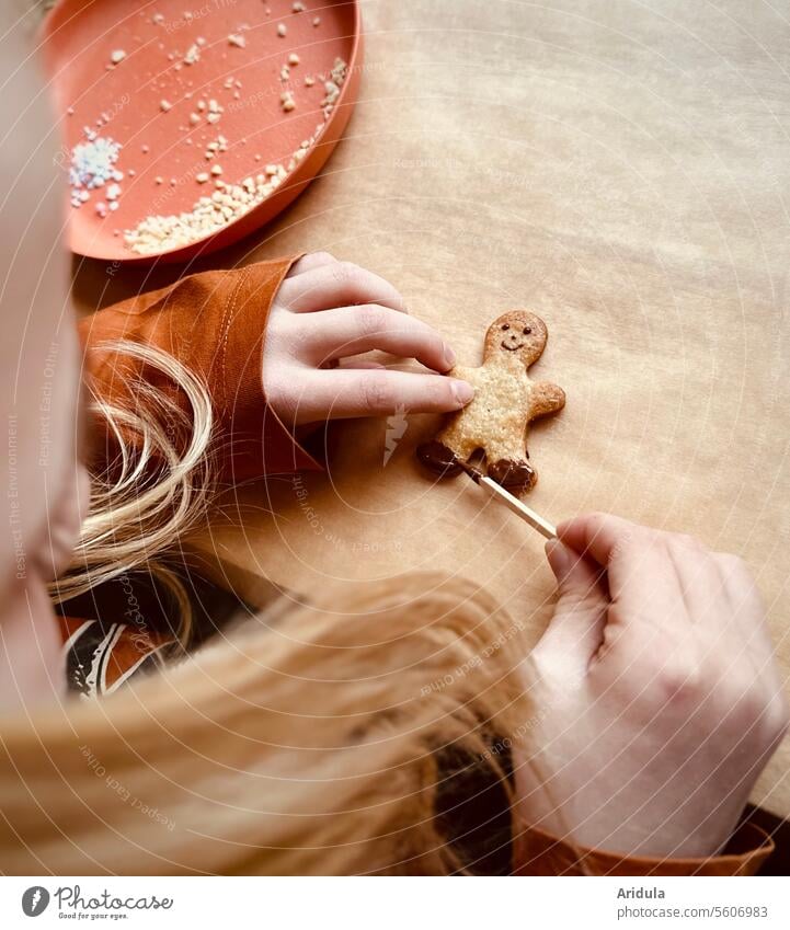 Kind gestaltet ein kleines Keksmännchen mit Schokokade Backen Plätzchen ausstechen Vorfreude Hand Vorweihnachtszeit naschen Backpapier Plätzchen backen