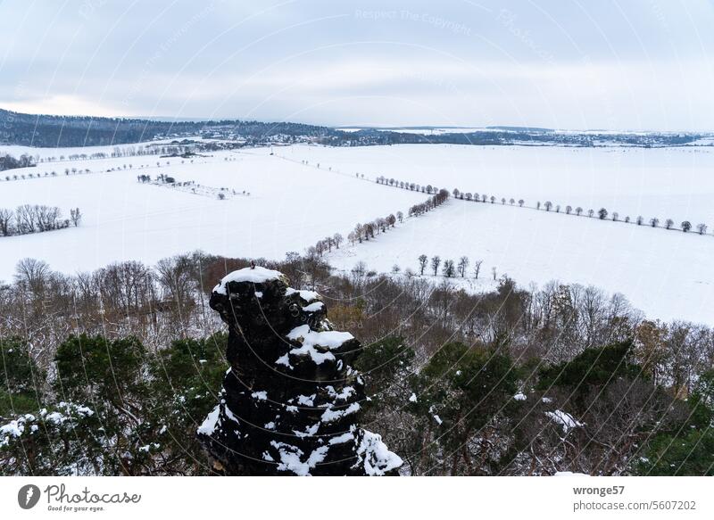 Verschneite Winterlandschaft mit einem Dorf am oberen Bildrand und solitären Felsen im Vordergrund Schneelandschaft Winterstimmung Wintertag kalt weiß
