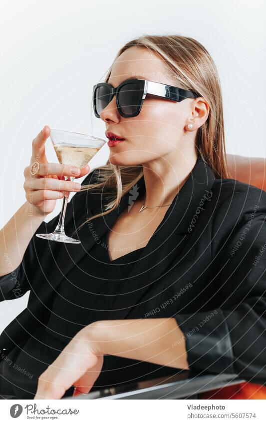Lady Boss in total schwarzem Look sitzt im Sessel und trinkt Wein, Wochenende jung Frau Martini Mode Armsessel Stil Anzug Jacke unabhängig Chef Model trinken