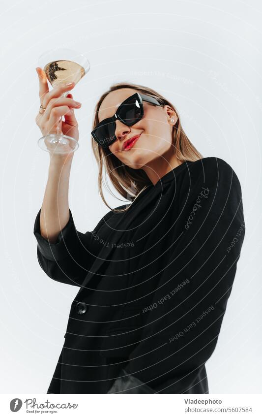 Frau in schwarzem Look und Sonnenbrille hält ein Glas Sekt und jubelt Wein funkelnd jubelnd trinken Alkohol Weinglas weiß Lächeln allein Feier Beteiligung schön