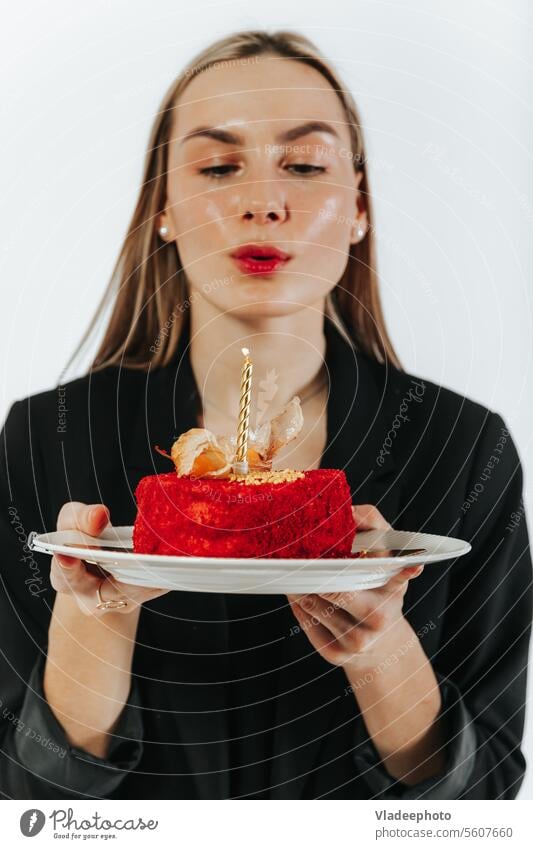 Ausblasen der Geburtstagskerzen. Attraktive junge Frau, die sich etwas wünscht, während sie einen roten Kuchen hält Wunsch Kerze Schlag feiern attraktiv allein