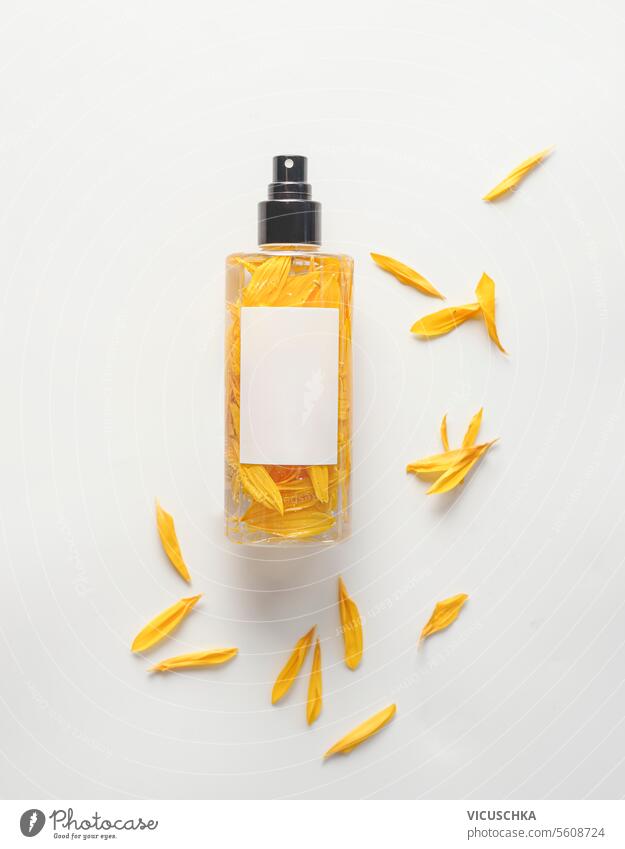 Sprühflasche mit gelben Blütenblättern auf weißem Hintergrund, natürliches Parfüm und ätherisches Öl Essenz, Ansicht von oben Spray Flasche weißer Hintergrund