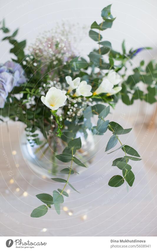 schöner minimaler Blumenstrauß mit Frühlingsblumen und Eukalyptusblättern. Frische elegante Heimdekoration. Florist Arbeit. Salon Vase Dekor heimwärts