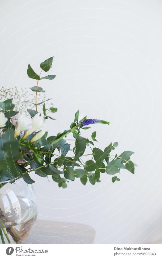 schöner minimaler Blumenstrauß mit Frühlingsblumen und Eukalyptusblättern. Frische elegante Heimdekoration. Florist Arbeit. Salon Vase Dekor heimwärts