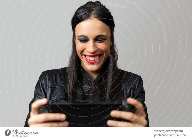 Eine junge Frau mit rotem Lippenstift lacht fröhlich, während sie mit einer Handheld-Videospielkonsole spielt, die sie in den Händen hält Spielen Konsole Spaß
