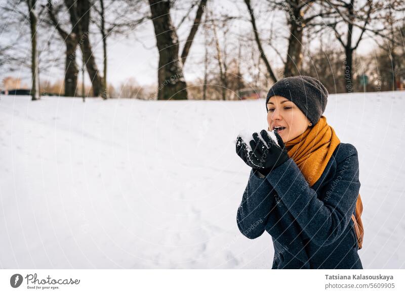 Eine Frau bläst im Winter den Schnee von ihren Handflächen kalt Fröhlichkeit Glück Freude Menschen Person Erwachsener blasend Mantel heiter Einzelperson Schlag