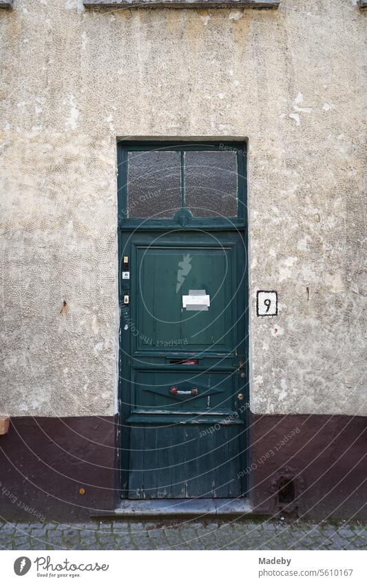Schöne alte Haustür aus Holz in Grün mit Hausnummer Neun in alter verwaschener Fassade als Teil des Unesco Weltkulturerbe in den Gassen der Altstadt von Brügge in Westflandern in Belgien