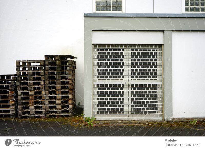 Gestapelte Europaletten aus Holz vor einem weißen Gebäude mit vergitterter Tür auf dem Hof eines Winzer in Traben-Trarbach an der Mosel im Kreis Bernkastel-Wittlich in Rheinland-Pfalz
