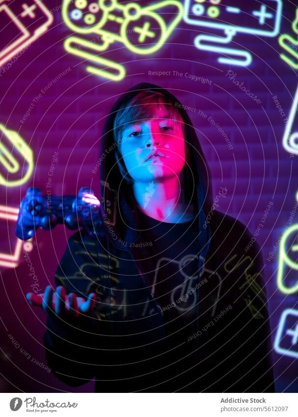 Jugendlicher Gamer mit Controller in neonbeleuchtetem Raum Teenager Spieler Regler Neonlicht Spielen Symbol elektronisch Entertainment Videospiel Freizeit