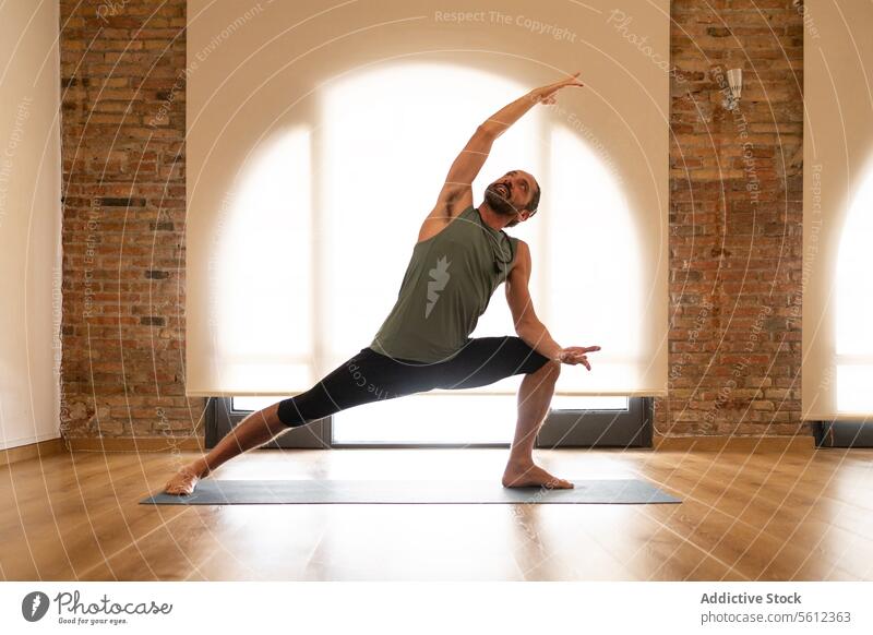 Mann übt Yoga in einem sonnigen Studio Pose Unterlage Atelier Übung friedlich gut beleuchtet Baustein Wand hölzern Stock Gesundheit Wohlbefinden Fitness üben
