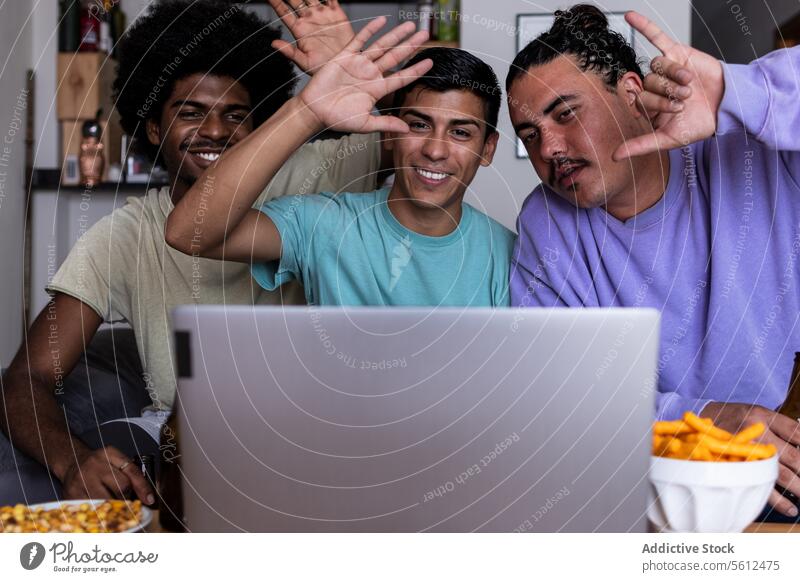 Videoanrufe mit Freunden auf dem Laptop zu Hause Lächeln Anruf Lifestyle Wohnzimmer gestikulieren winken Hand heiter Freizeitkleidung Drahtlos Computer Afrohaar