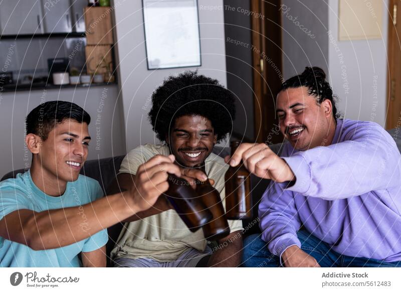 Fröhliche Freunde bei einem Drink zu Hause Röstung Bier Flasche heiter Wohnzimmer Alkohol Wochenende Feiertag Freundschaft Lächeln Zusammensein Lifestyle