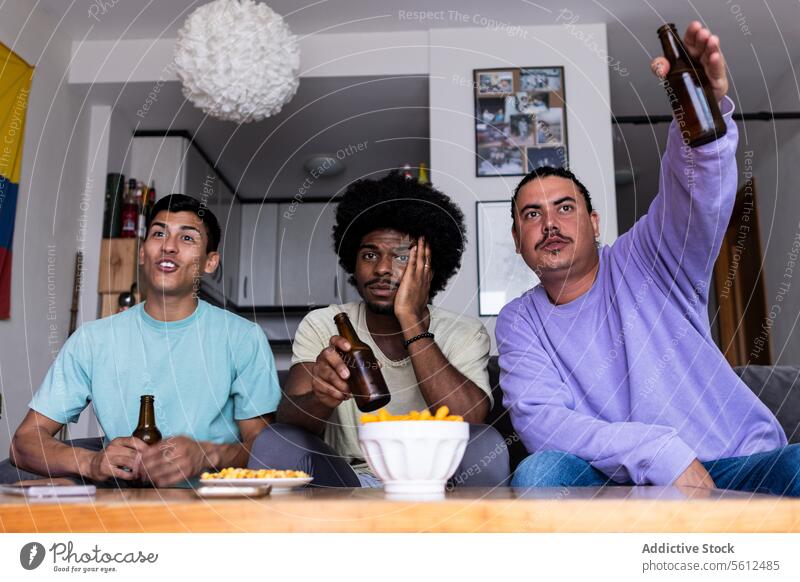 Männliche Fans mit Bier, die das Spiel zu Hause verfolgen Freunde zuschauend Streichholz Flasche Snack Wohnzimmer enttäuscht Tisch Sport sitzen Sofa Wochenende