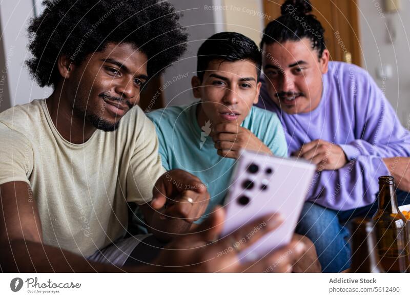 Männliche Freunde machen ein Selfie zu Hause Lächeln Afrohaar Smartphone Freizeit Zusammensein Wohnzimmer Freundschaft Wochenende Mobile Telefon Bier Flasche