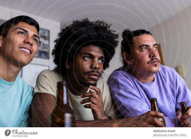 Ernsthafte männliche Fans, die sich zu Hause ein Sportspiel ansehen Freunde Ventilator Nervös ernst zuschauend Streichholz Spiel Konzentration Freizeitkleidung