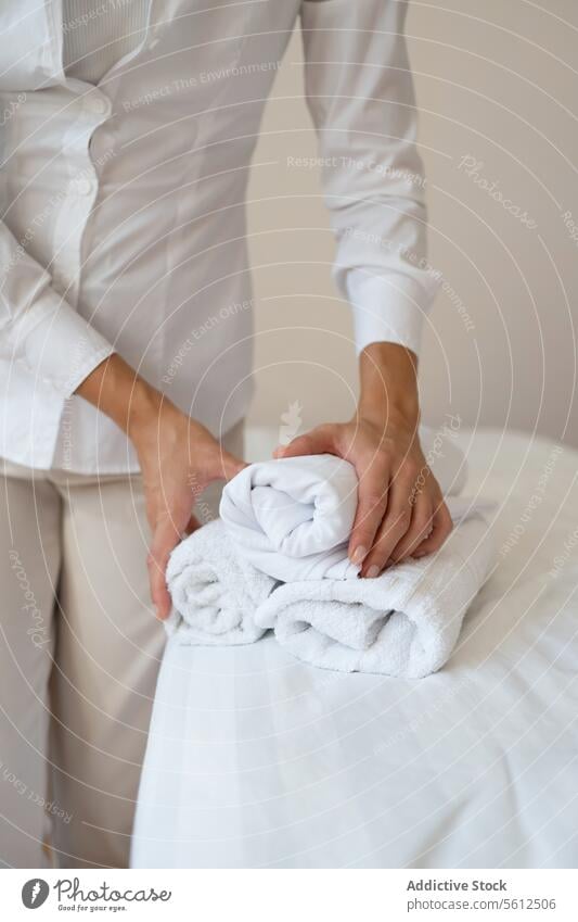 Crop Hand von anonymen weiblichen Massage-Therapeutin in weißer Uniform stehen und halten sauber aufgerollt Handtücher während der Arbeit in Spa-Salon Handtuch