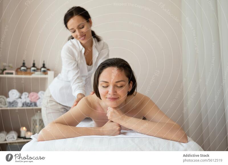 Schöne oben ohne weiblichen Kunden lächelnd liegen bequem auf dem Bett und erhalten Rücken-Therapie-Massage von Frau Therapeutin im Spa-Salon Frauen schön